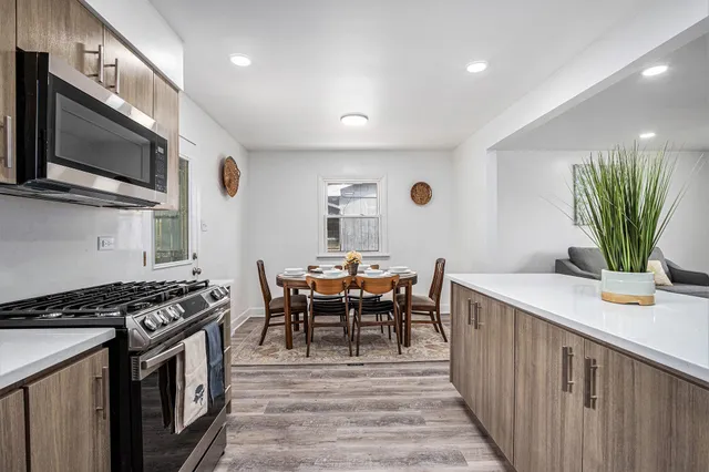 a kitchen with stainless steel appliances a table chairs and a stove top oven