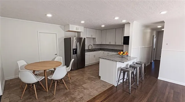 a kitchen with stainless steel appliances a refrigerator a stove a dining table and chairs with wooden floor