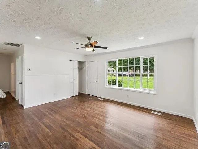 a view of an empty room with a window and wooden floor