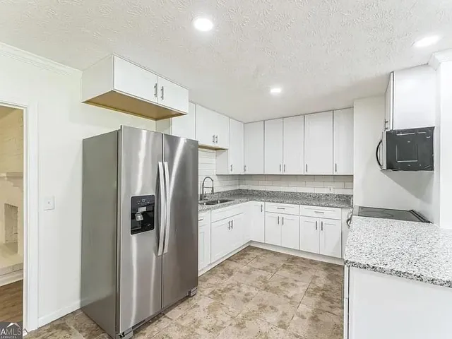 a kitchen with granite countertop a refrigerator and a sink