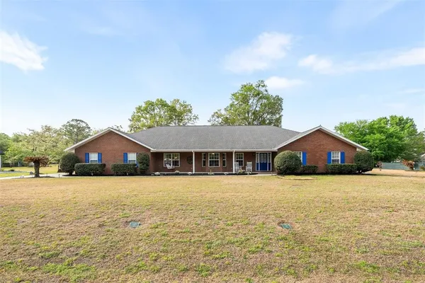 a front view of house with yard and trees in the background