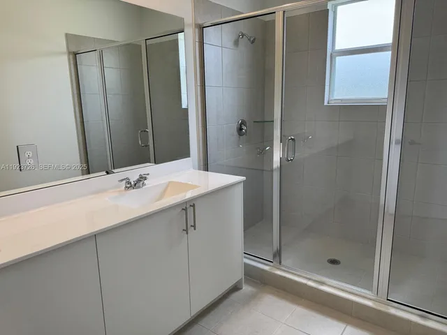 a bathroom with a shower sink and mirror
