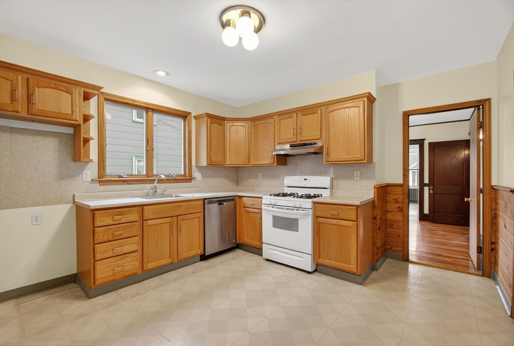 67 Irving Street Somerville, MA 02144 - Photo 11 of 40 a kitchen with granite countertop a stove a sink and a refrigerator