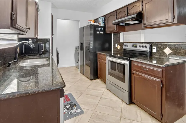 a kitchen with stainless steel appliances granite countertop a sink stove and refrigerator