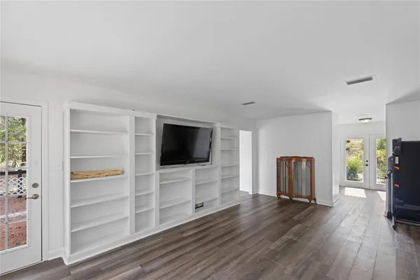 a view of an empty room with window and wooden floor