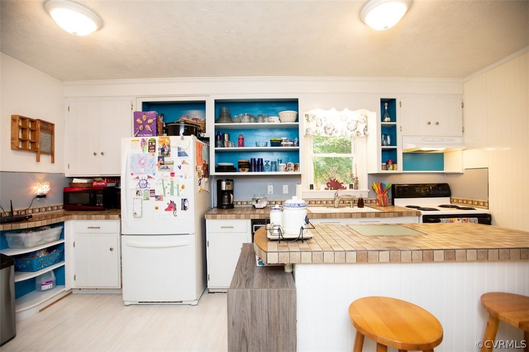 1213 West Osborn Road Farmville, VA 23901 - Photo 14 of 37 a kitchen with stainless steel appliances a stove a refrigerator white cabinets and couches with wooden floor
