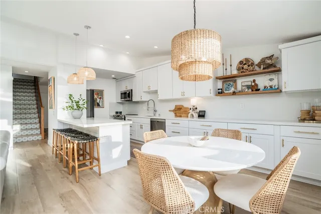 a kitchen with stainless steel appliances granite countertop a sink dishwasher a stove a dining table and chairs with wooden floor