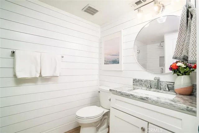 a bathroom with a granite countertop sink vanity mirror and toilet