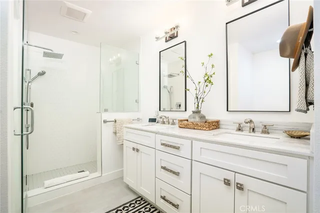 a bathroom with a double vanity sink mirror and shower