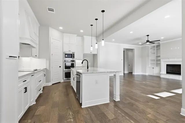 a large kitchen with stainless steel appliances kitchen island a stove a sink dishwasher and a refrigerator with white cabinets