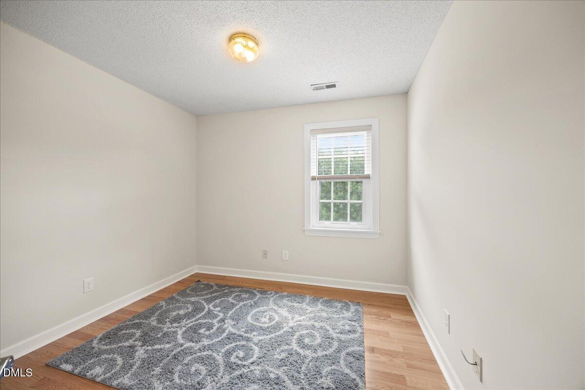 1932 Stroll Circle Fuquay-Varina, NC 27526 - Photo 19 of 24 an empty room with wooden floor and windows