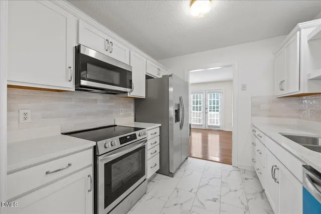 a kitchen with stainless steel appliances granite countertop white cabinets a stove top oven and sink