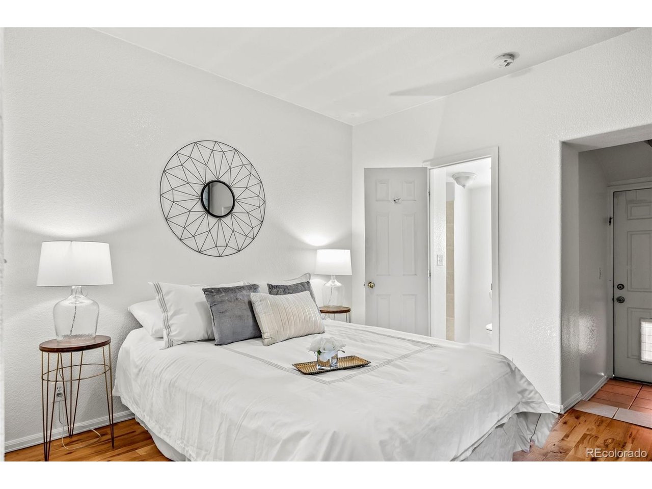 321 Inca Street Denver, CO 80223 - Photo 13 of 27 a bedroom with a bed and a lamp on table