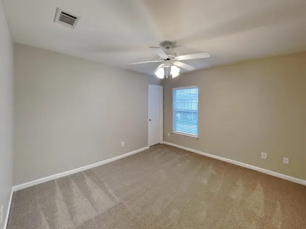 an empty room with windows and fan