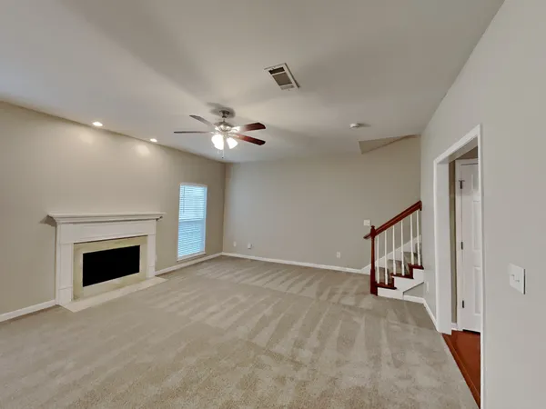 a view of an empty room with chandelier fan and fire place