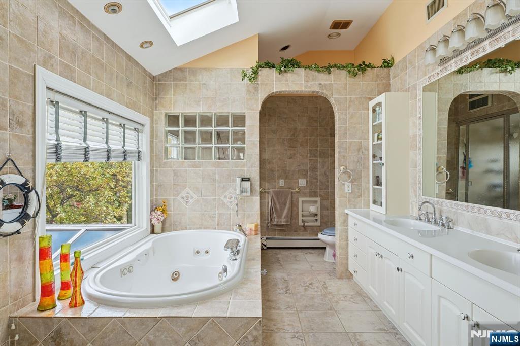 703 Stewart Street Ridgefield, NJ 07657 - Photo 18 of 38 a spacious bathroom with a tub sink and mirror