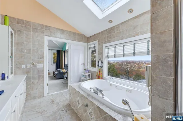 a bathroom with a granite countertop tub sink and mirror