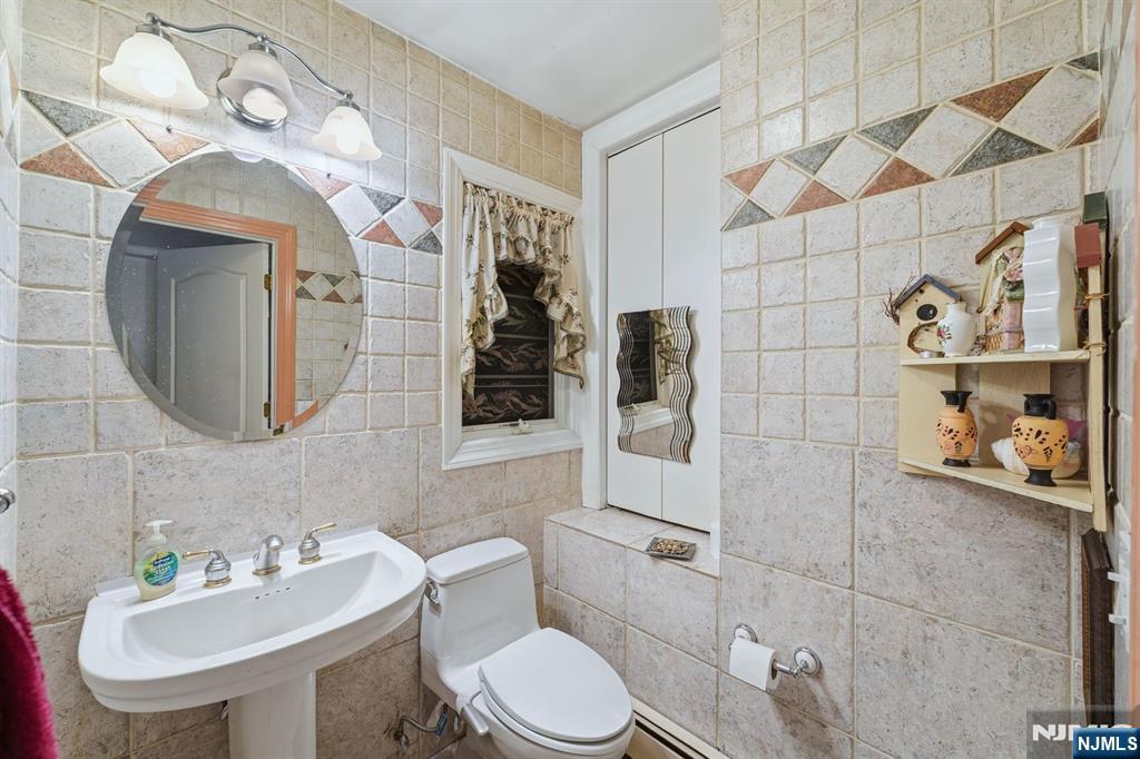 703 Stewart Street Ridgefield, NJ 07657 - Photo 23 of 38 a bathroom with a toilet sink and mirror