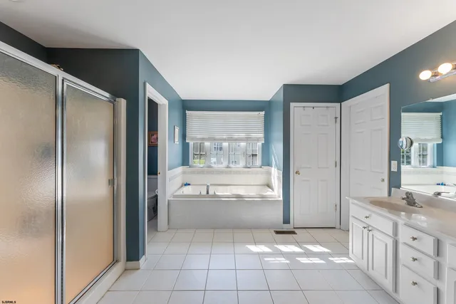a bathroom with a granite countertop bathtub shower and mirror
