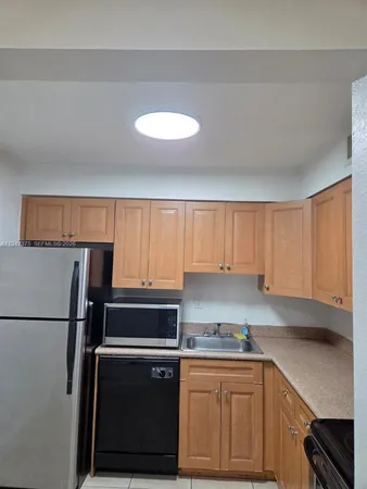 a kitchen with a sink a refrigerator and cabinets