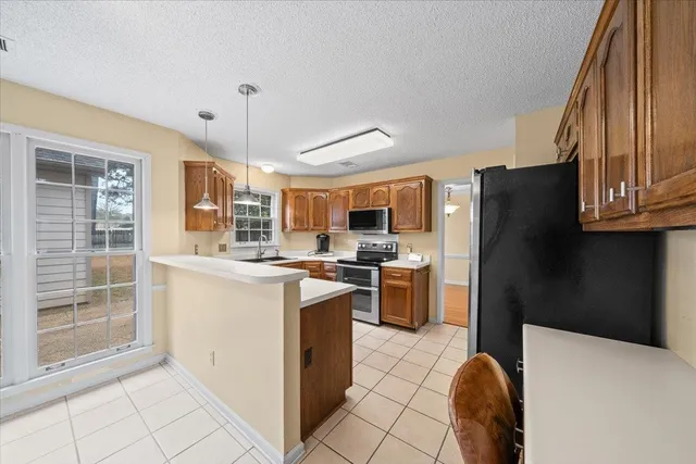 a kitchen with a refrigerator a stove top oven a sink dishwasher and wooden cabinets