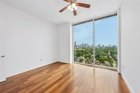 an empty room with wooden floor fan and windows