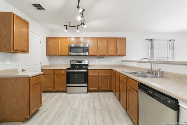 a kitchen with kitchen island granite countertop a sink cabinets stainless steel appliances and a counter space