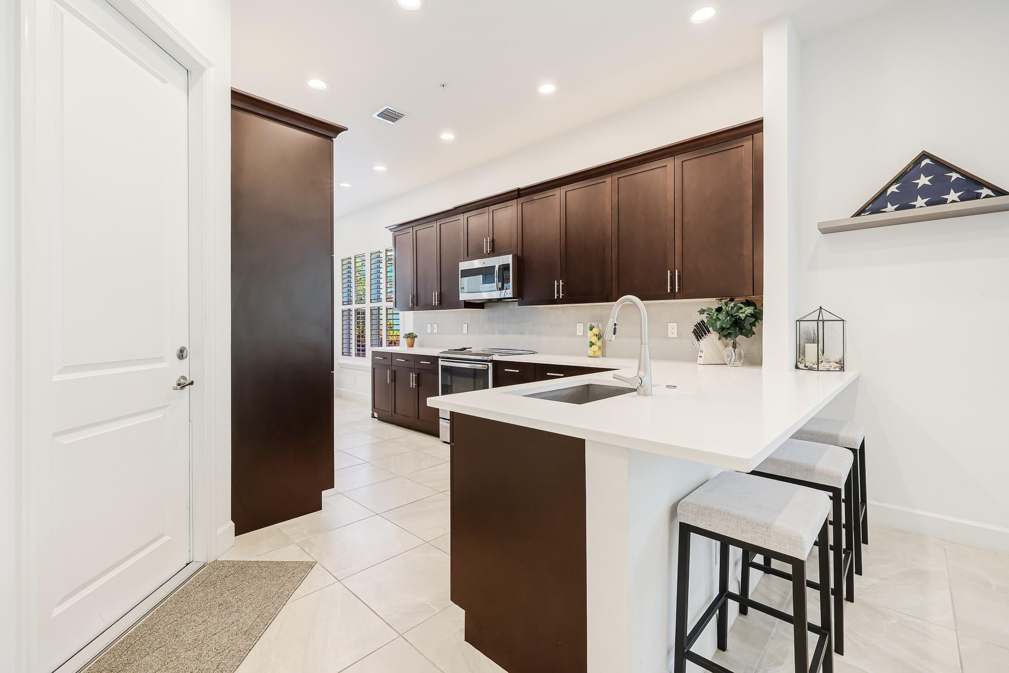 22954 Clear Echo Drive, Unit 31 Boca Raton, FL 33433 - Photo 6 of 38 a kitchen with a refrigerator a stove and a microwave with wooden floor