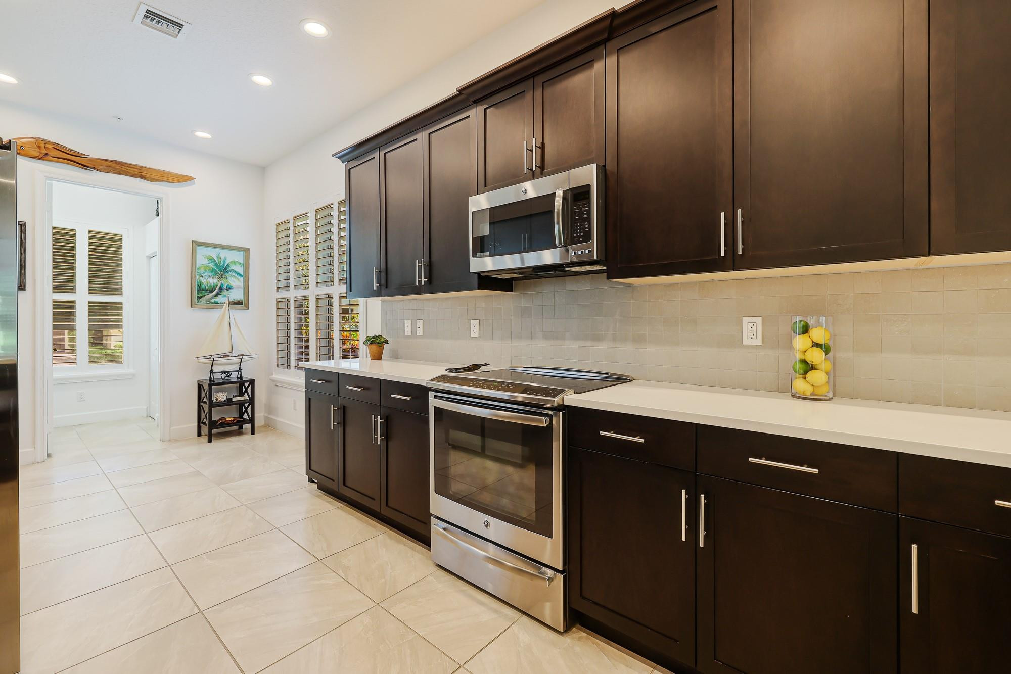 22954 Clear Echo Drive, Unit 31 Boca Raton, FL 33433 - Photo 7 of 38 a kitchen with stainless steel appliances granite countertop a stove a sink and a microwave