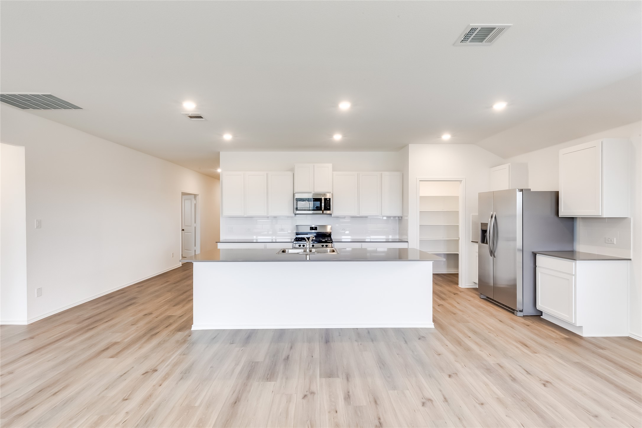 2000 Gilmer Way Leander, TX 78641 - Photo 8 of 39 Kitchen with appliances with stainless steel finishes, recessed lighting, light wood-style flooring, and white cabinets
