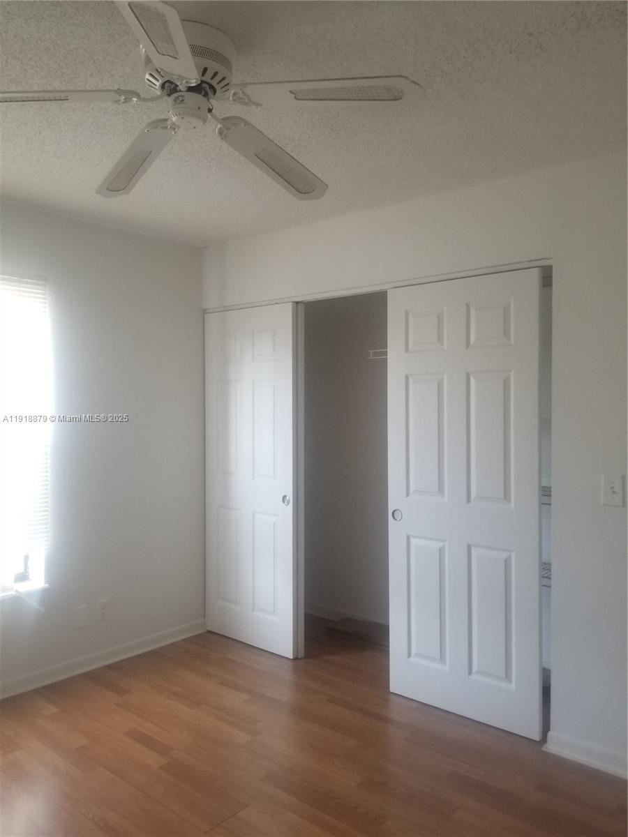 15 Crossings Circle, Unit A Boynton Beach, FL 33435 - Photo 11 of 14 an empty room with wooden floor fan and windows