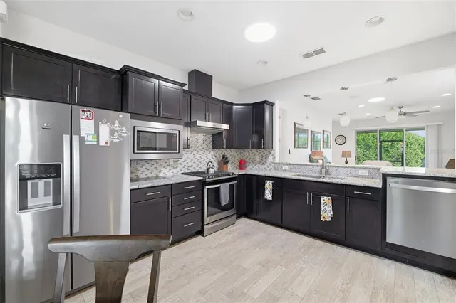 a large kitchen with stainless steel appliances granite countertop a refrigerator a sink dishwasher a stove and a refrigerator