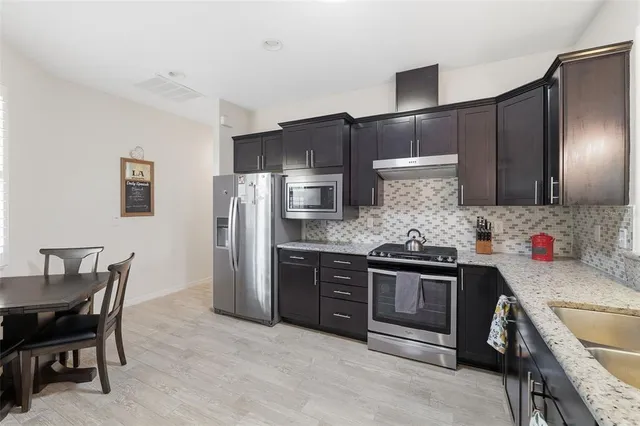 a kitchen with stainless steel appliances granite countertop a sink stove and refrigerator