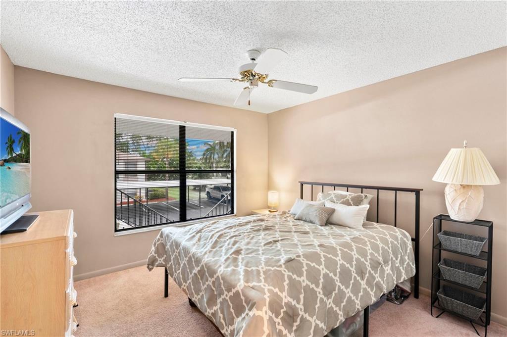 236 Pebble Beach Circle, Unit A202 Naples, FL 34113 - Photo 15 of 25 a bedroom with a large bed and a chandelier