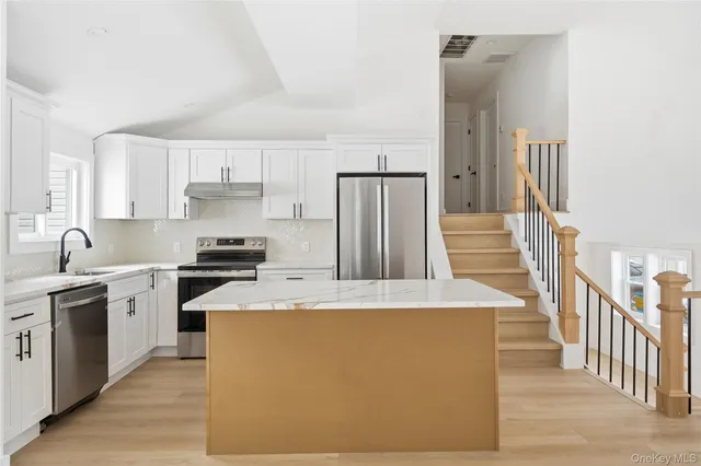 a kitchen with stainless steel appliances granite countertop a refrigerator a stove a sink and white cabinets