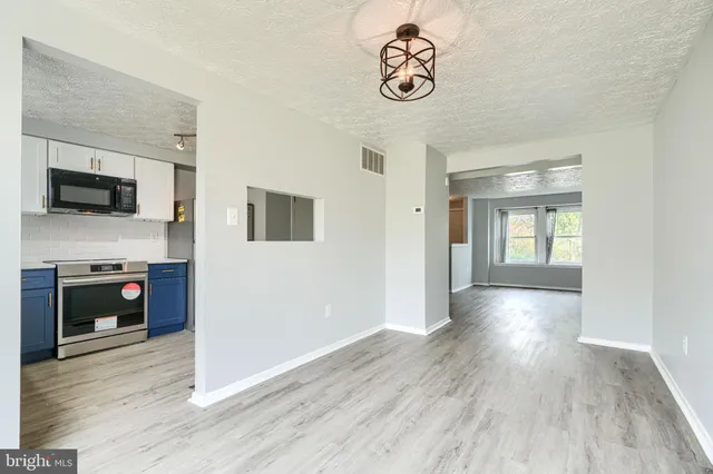 a view of a livingroom with wooden floor and a kitchen