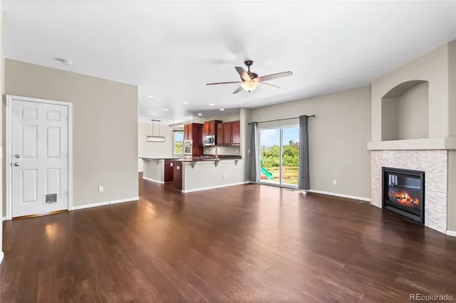 a view of a living room with wooden floor and a kitchen