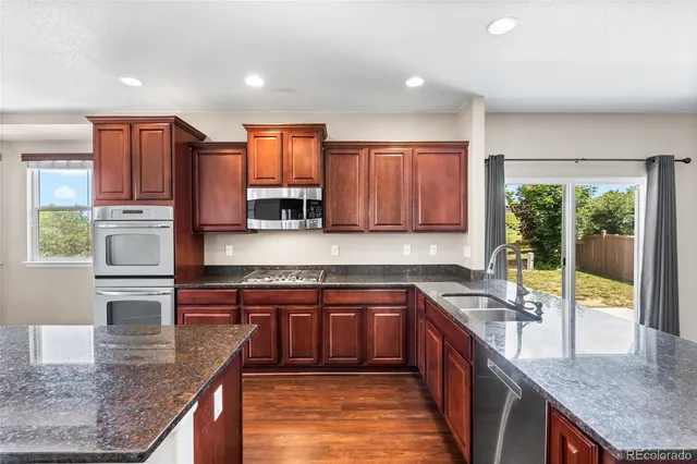 a kitchen with stainless steel appliances granite countertop a stove a sink and a microwave