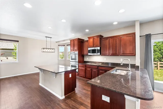 a kitchen with stainless steel appliances granite countertop a sink a stove and a wooden floors