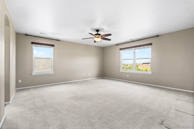 an empty room with windows and ceiling fan