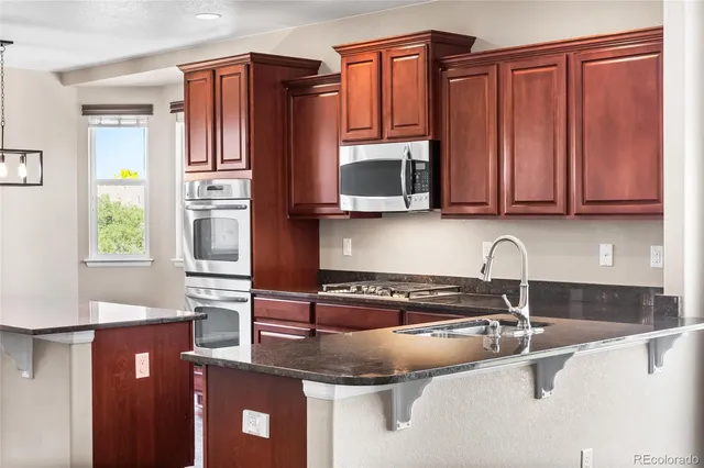 a kitchen with granite countertop a sink a stove and cabinets