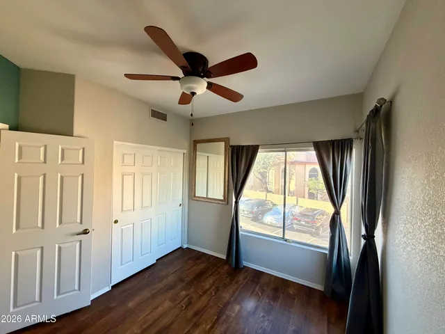 a view of empty room with wooden floor and fan