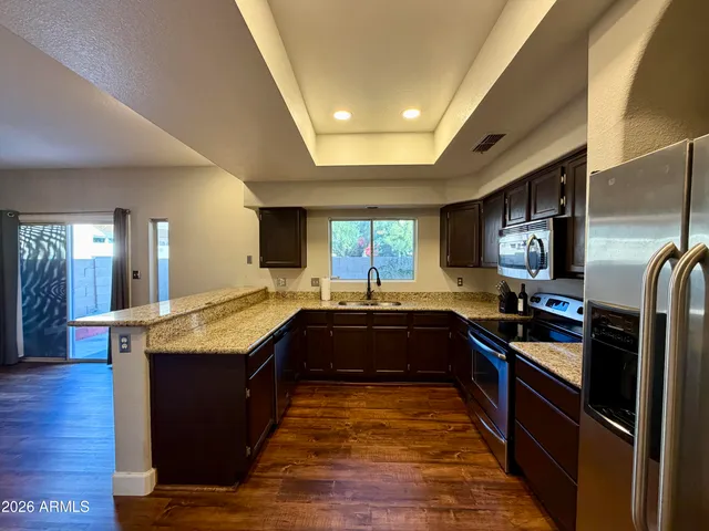 a large kitchen with granite countertop a large counter top and stainless steel appliances