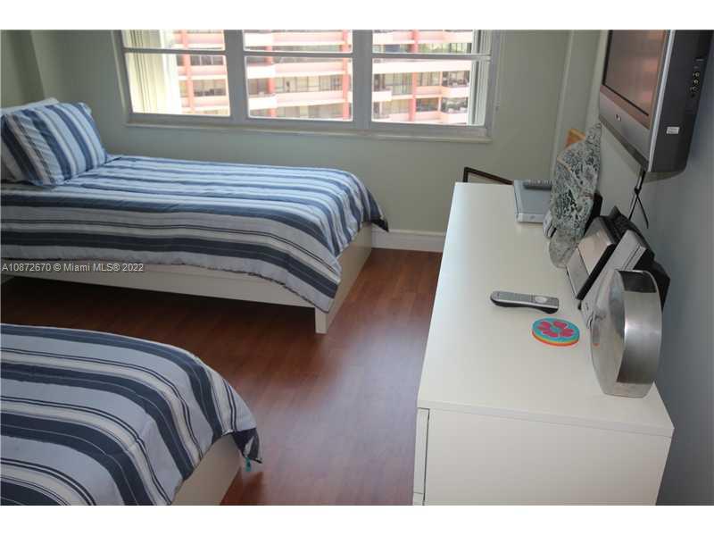 5161 Collins Avenue, Unit 902 Miami Beach, FL 33140 - Photo 14 of 43 a bedroom with a bed and a flat tv screen on the dresser