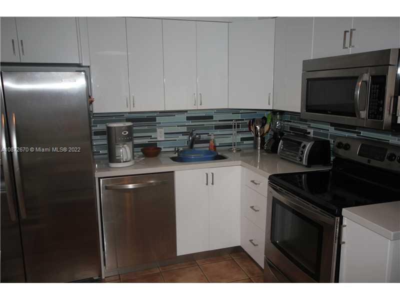 5161 Collins Avenue, Unit 902 Miami Beach, FL 33140 - Photo 9 of 43 a kitchen with a refrigerator and a stove top oven