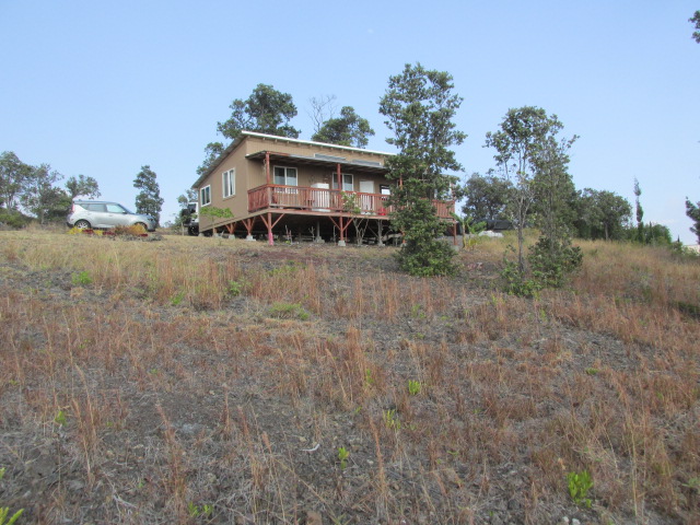 92-8629 Koa Lane Ocean View, HI 96704 - Photo 9 of 12 a front view of house with yard and trees in the background