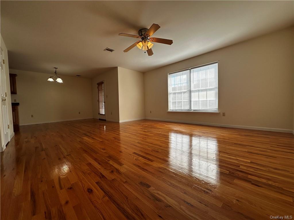 105 South Montgomery Street, Unit B1 4 Walden, NY 12586 - Photo 6 of 20 Unfurnished living room with dark wood-type flooring and ceiling fan with notable chandelier