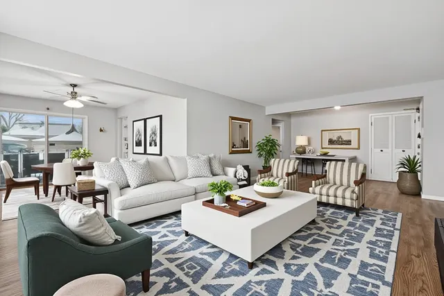 a living room with furniture potted plant and open kitchen view
