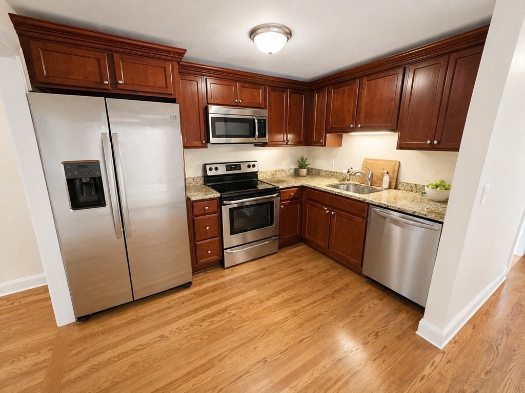 92 Sandwich Road, Unit 4D Bourne, MA 02532 - Photo 4 of 18 a kitchen with stainless steel appliances granite countertop white cabinets a sink a stove a refrigerator and microwave