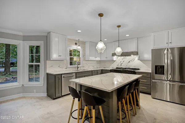 a kitchen with granite countertop a table chairs a sink and refrigerator